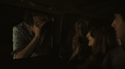Group Sitting in Dark Room One Covering Face