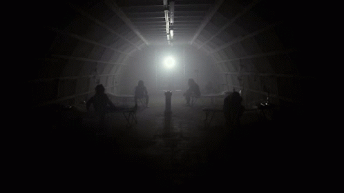 Group Sitting in Dark Room With Light Through Ceiling