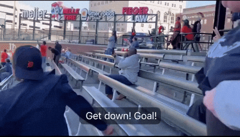 Group Sitting in Stadium Sign Says Get Down