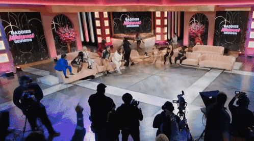 Group Sitting On Couch In Front Of Baddies Reunion Sign GIF