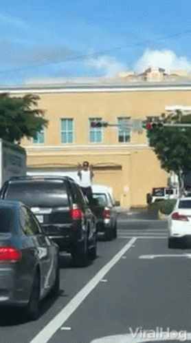 Guy Performing At The Back Of A Car While Traffic GIF