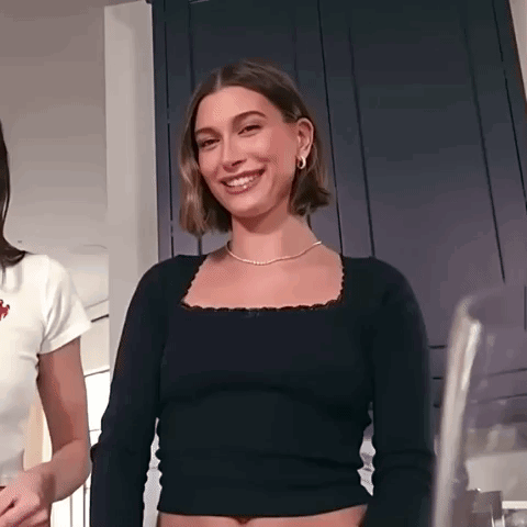 Hailey Baldwin Is Wearing A Black Crop Top And A Gold Necklace . GIF