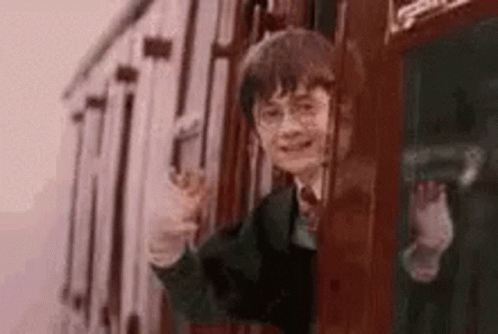 harry potter is waving while riding a train .