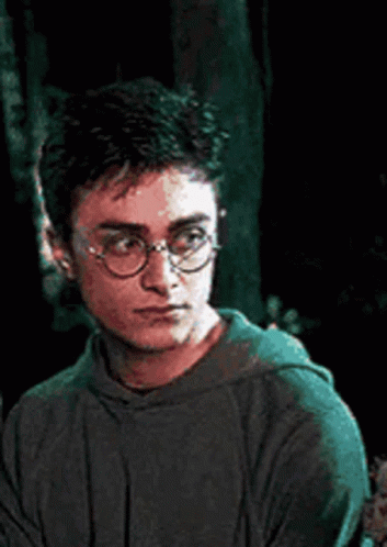 Harry Potter Is Wearing Glasses And A Green Hoodie While Looking Down . GIF
