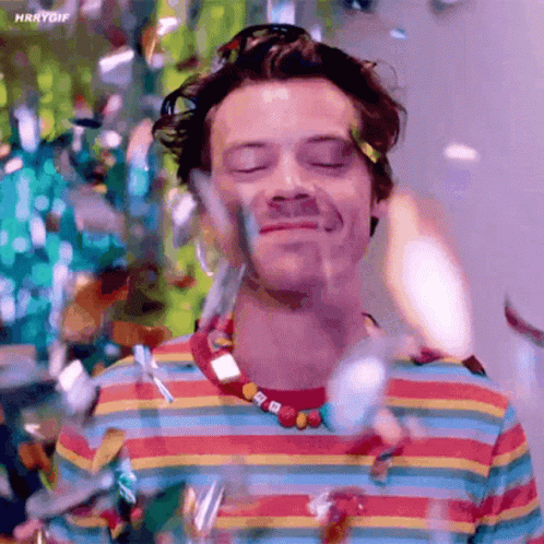 Harry Styles in Colorful Striped Shirt Holding Water