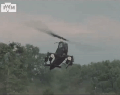 Helicopter Flying Over Forest With IWM Letters