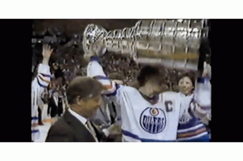 Hockey Player Holding Trophy With Man Behind