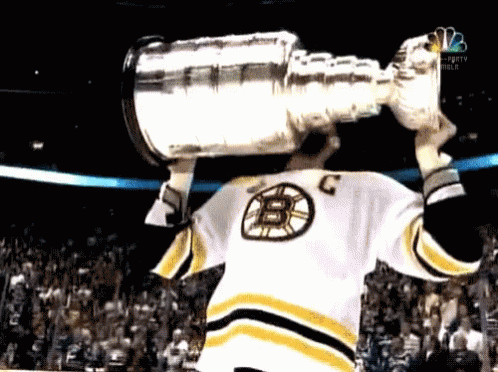 Hockey Player in B Jersey Holding Trophy Over Head