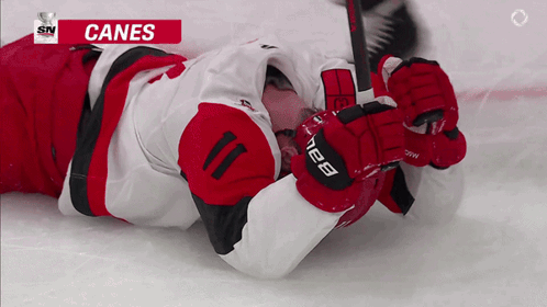 Hockey Player Laying on Ice With Canes