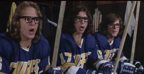 Hockey Players Sitting in Locker Room With Sticks