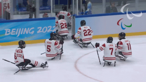 Hockey Players Sitting On Ice In Front Of Beijing 2022 Sign GIF