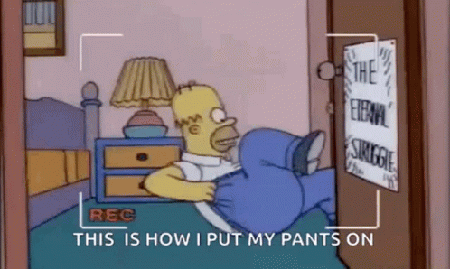Homer Simpson Is Laying On A Bed With His Pants On And A Camera Recording Him . GIF