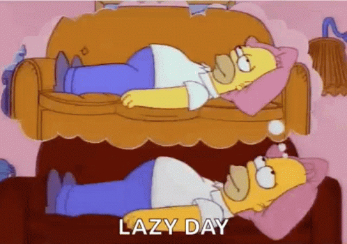 homer simpson is laying on a couch with a pink pillow on his head .
