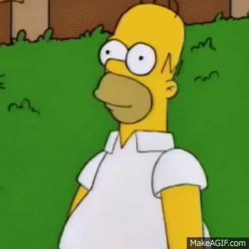 Homer Simpson Is Standing In The Grass Wearing A White Shirt And Looking At The Camera . GIF