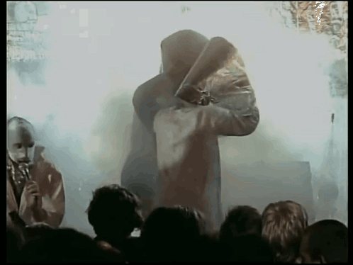 Hooded Man Holding Sword Before Crowd