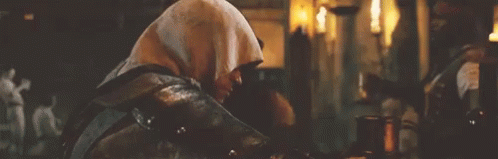 Hooded Man Sitting in Dark Room With Candles