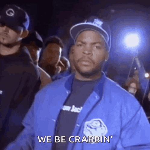 Ice Cube Is Wearing A Blue Jacket And A Hat While Standing In Front Of A Crowd Of People . GIF
