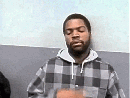 Ice Cube Is Wearing A Plaid Shirt And A Hoodie While Standing In Front Of A Wall . GIF