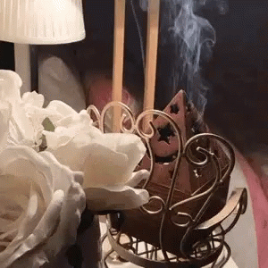 Incense Burner Smoking Beside Lamp And Flowers GIF