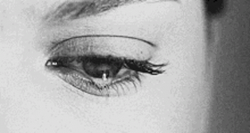 It Is A Black And White Photo Of A Woman 'S Eye With A Tear Coming Out Of It . GIF