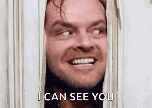 Jack Nicholson From The Shining Is Smiling While Looking Through A Door . GIF