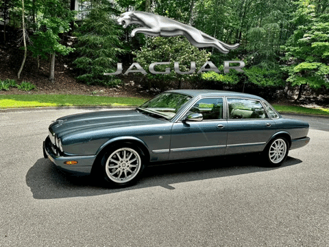 Jaguar Car Parked In Front Of Large Jaguar Logo GIF