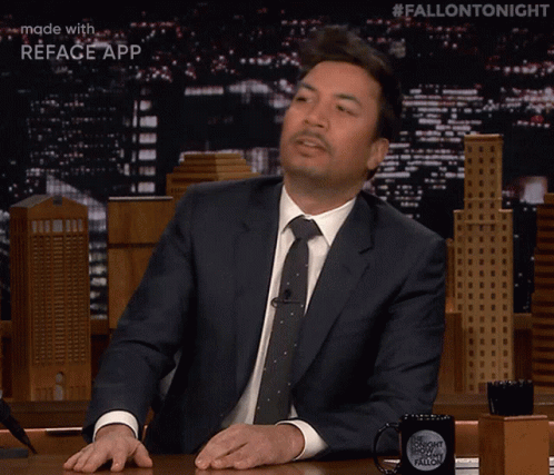Jimmy Fallon Is Sitting At A Table With A Fallon Tonight Mug GIF