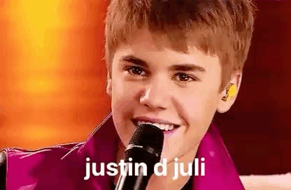 Justin Bieber Is Smiling While Holding A Microphone In His Hand . GIF