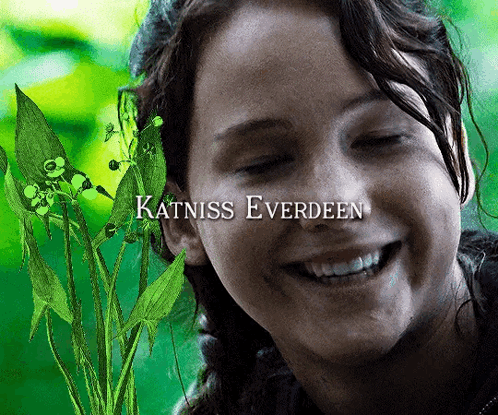 Katniss Everdeen Is Smiling With A Plant Behind Her GIF