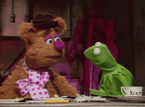 Kermit The Frog And Fozzie Bear Are Sitting Next To Each Other On A Table GIF