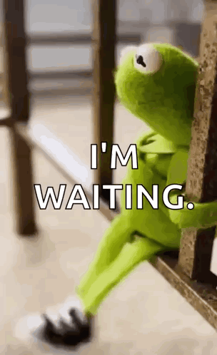 kermit the frog is sitting on a bench with the words `` i 'm waiting '' written above him .