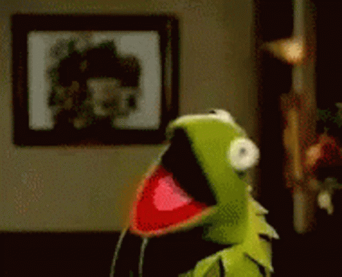 Kermit The Frog Is Standing In A Room With His Mouth Open And A Picture On The Wall Behind Him . GIF