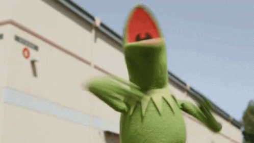 Kermit The Frog Is Standing In Front Of A Building . GIF