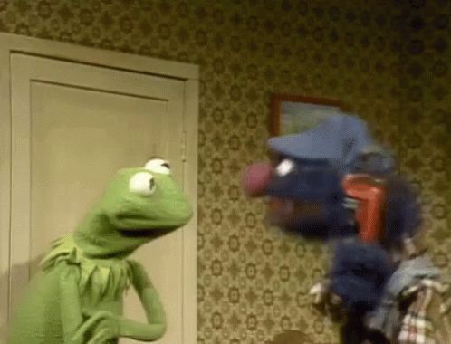 Kermit The Frog Is Standing Next To A Puppet In A Room . GIF
