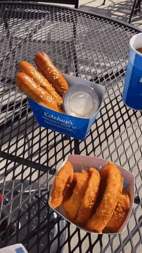 Ketchup 'S Pretzels And Onion Rings Are On A Table Outside GIF