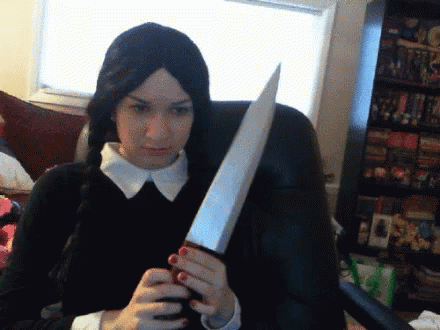 Girl Looks Like Wednesday Holding Knife While Seating GIF