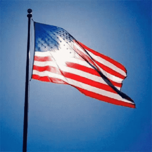 Large American Flag Flying In Wind Blue Sky GIF