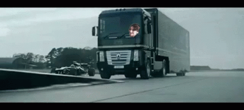 Large Black Truck Driving Next to Race Car