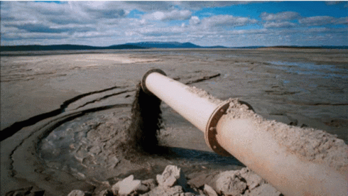 Large Pipe Pouring Sand Into Rocky Water GIF