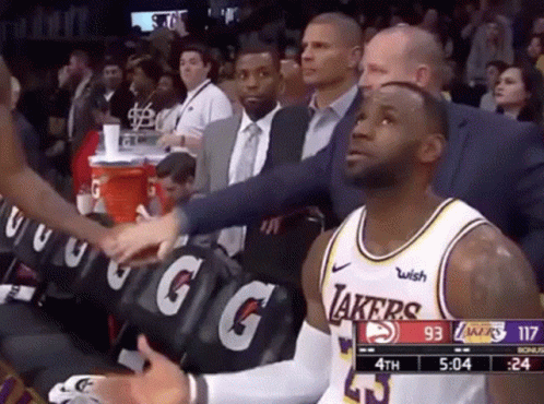 Lebron James Is Sitting In The Stands During A Basketball Game While A Man Shakes His Hand . GIF