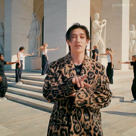 Leopard Coat Man Holding Microphone to Ponytail Woman