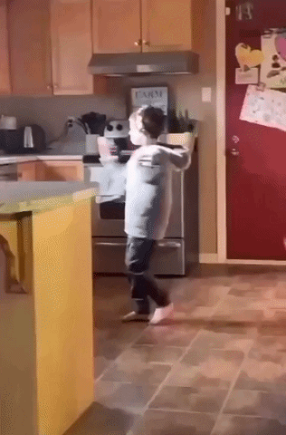 Little Boy Dancing In Kitchen With Farm Sign On Refrigerator GIF