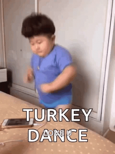 Little Boy in Blue Shirt Dancing on Bed Next to Phone
