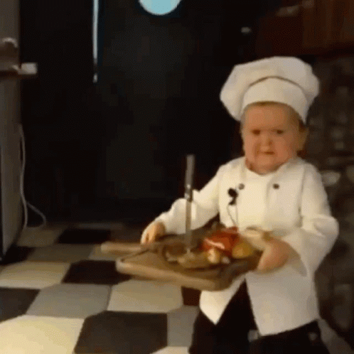 Little Boy in Chef Hat Holding Cutting Board with Meat