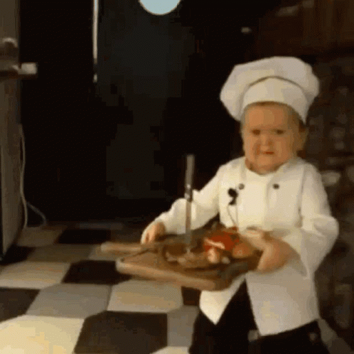 Little Boy in Chef Uniform Holding Cutting Board with Meat