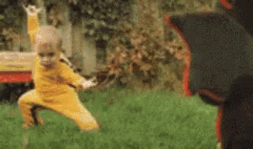 Little Boy In Yellow Practicing Martial Arts With Black Bear GIF