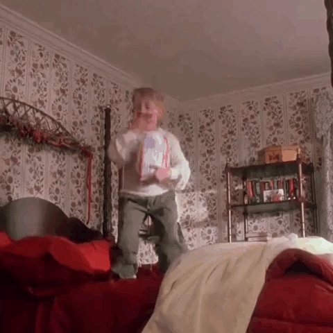Little Boy Jumping on Bed Holding Book