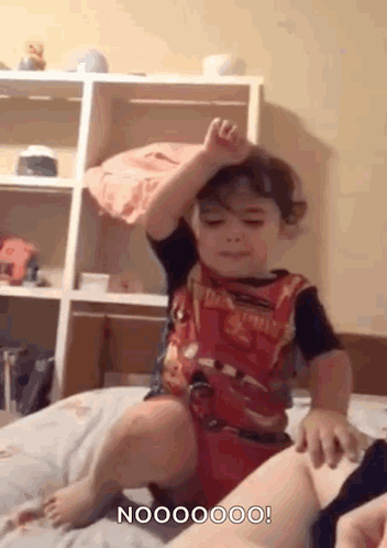 Little Boy Sitting On Bed Hand Up GIF