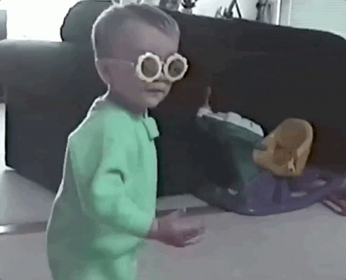 Little Boy With Glasses and Green Outfit Beside Couch