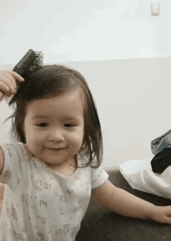 Little Girl Brushing Hair And Smiling GIF